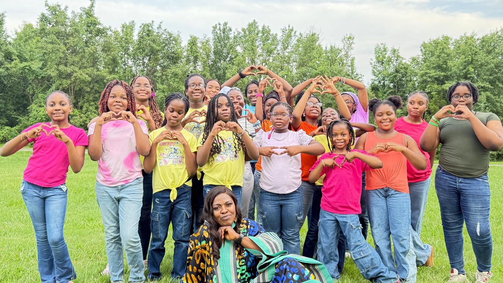 Girls making heart shapes with their hands at an outdoor Responsible Girls Forum gathering